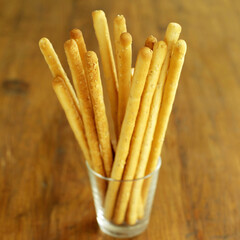Italian breadsticks in glass on wooden table