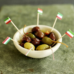 Fresh Italian olives in small ceramic bowl with Italian flag picks
