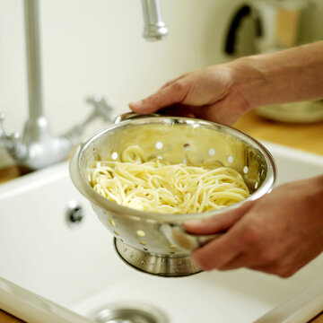Draining spaghetti in the sink with colander