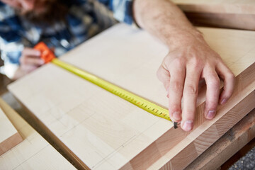 Furniture maker with measuring tape when measuring wood