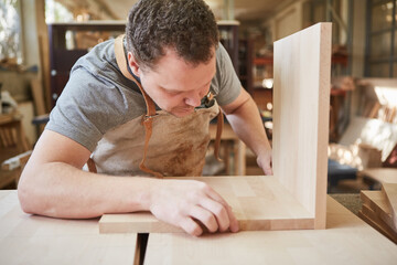 Furniture maker in carpentry builds shelf from wood