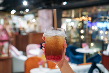 Apple tea with strawberry popping. Woman holding a plastic cup of apple tea with strawberry popping. (center)