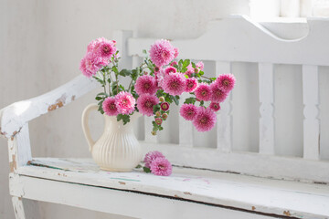 Fototapeta na wymiar pink chrysanthemums in jug on old white wooden bench