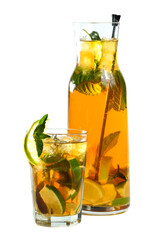 Mint tea with limes in a glass and a full jug on a white background