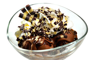 Chocolate ice cream sundae with sweet tubules, whipped cream and chocolate flakes in glass cup on white background