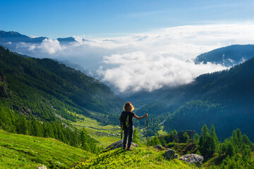 Woman resting on mountain top, looking at view dramatic landscape clouds over the valley, clear...