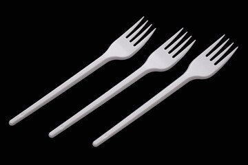 Three white plastic forks isolated on a black background.