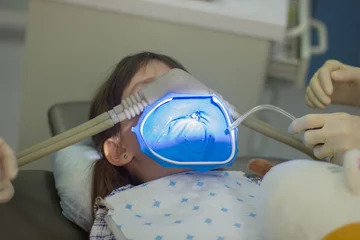 Poster Geavanceerde geneeskunde. Klein meisje bij de tandartspraktijk met verdoving tandheelkunde. Tandarts die de tanden van de patiënt behandelt in de kliniek. © Albert Ziganshin