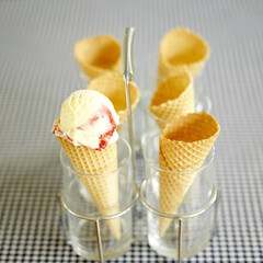 Raspberry ripple ice cream cone in holder on table with blue gingham cloth