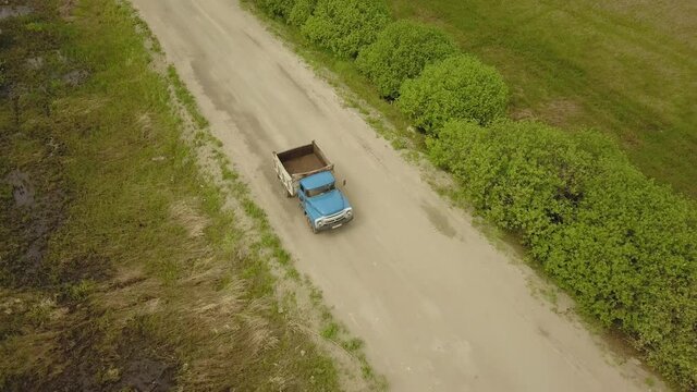 A flying camera shoots a truck passing in the fields below.