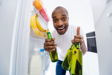 Portrait of his he nice attractive glad funky cheerful cheery guy looking in fridge taking limonade...