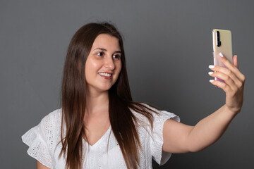 Smiling woman makes selfie on a smartphone. Happy girl photographs herself on a cell phone.