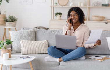 Home Office. Black Woman Checking Documents And Talking On Cellphone At Home