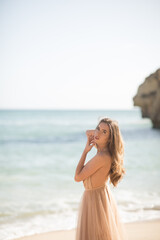 Fototapeta na wymiar Young female on beach wearing elegant dress. Beautiful Summer Woman on the Beach