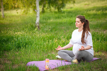 Healthy pregnant woman doing yoga in nature outdoors.