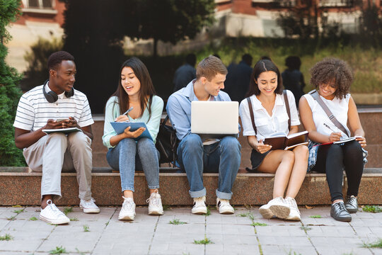 Group of happy teen high school students studying outdoors