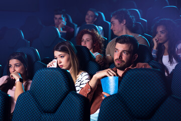 Group of people watching sad movie in cinema.