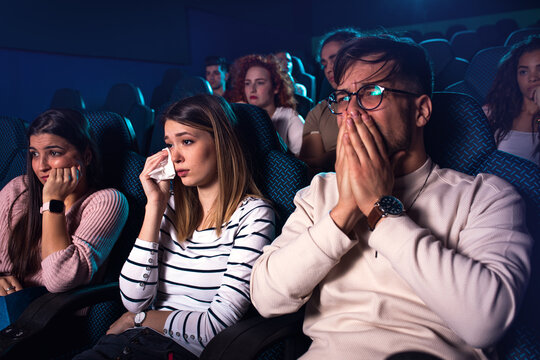 Group of people watching sad movie in cinema.