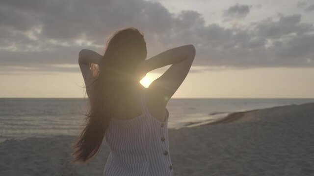 Unrecognizable female rumpling hair on beach in evening