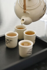 Pouring tea into teacups on tray