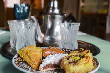 Close-up view of traditional arabic cupcakes (baklava) with a blurred arabic tea set as a background