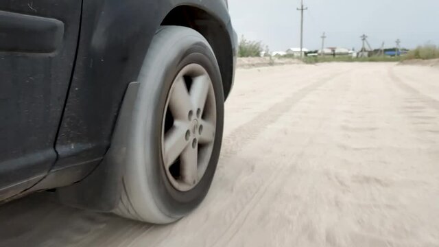 car suspension works on a sand . tire on car driving on hard road in summer