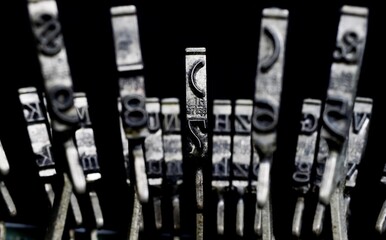 Macro closeup of isolated type bars of old typewriter with letters and symbols, black background