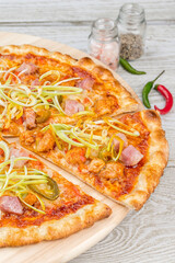 Meat pizza with sliced slice on a wooden board