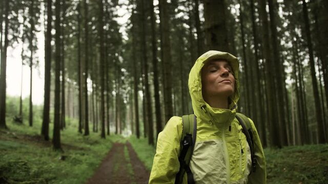 Woman putting on her hood in the rainy forest
