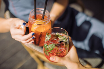 Women holding glasses of summer lemonade and toasting. Healthy lifestyle concept. Outdoors.