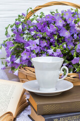 cup coffee (tea), books and bouquet flax in wicker basket