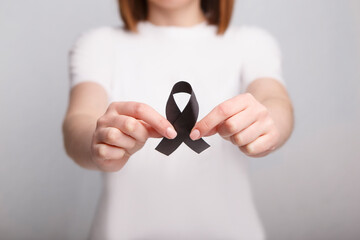 Unrecognizable woman holds awareness ribbon. Melanoma Cancer