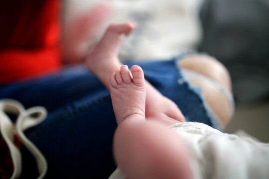 Feet of a newborn baby. Legs on a blue background. Baby feet, lifestyle family photoshoot. 
