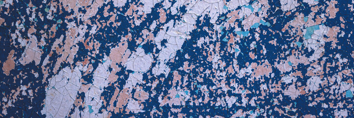 Peeling paint on the wall. Panorama of a concrete wall with old cracked flaking paint. Weathered rough painted surface with patterns of cracks and peeling. Grunge texture for wide panoramic background