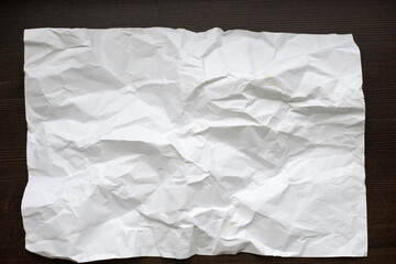 White crumpled paper on a dark wooden background.