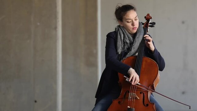 Mujer tocando con pasi&oacute;n el violonchelo al aire libre