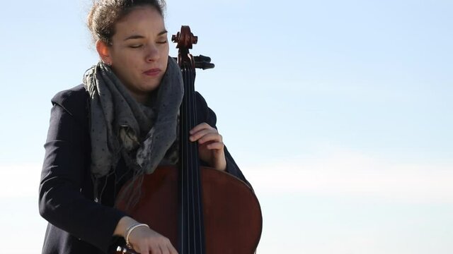 Mujer tocando con pasi&oacute;n el violonchelo al aire libre