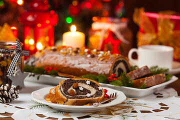 Fototapeta na wymiar Poppy seed roulade in Christmas decoration. Served with coffee or tea.