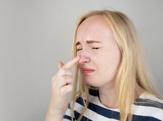 A young woman touches her nose, which is very painful. Medical care concept for difficulty...