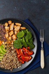 Salad with quinoa, avocado and chicken. Top view. Served on a black plate.