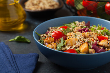 Salad with quinoa, avocado and chicken. Front view. Served in a blue bowl.