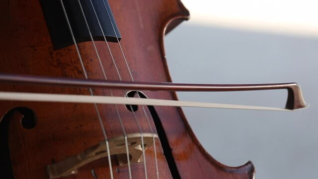 Detalle de un violonchelo mientras una mujer lo toca.