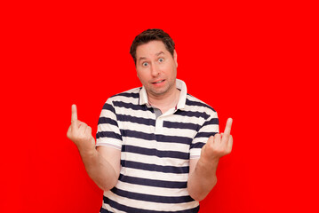 Middle age handsome man wearing casual t shirt over red background Showing middle finger.