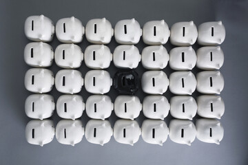 One black piggy bank surrounded by white piggy banks
