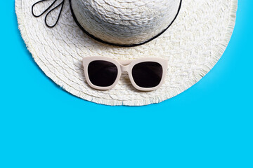 Sunglasses with summer hat on blue background. Enjoy holiday concept.
