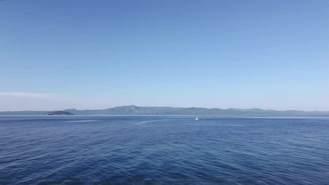Drone flying shot of fishing boat at calm sea in Greece. Aerial top view of caique sailing at Kassandra Chalkidiki peninsula with background Sithonia view.