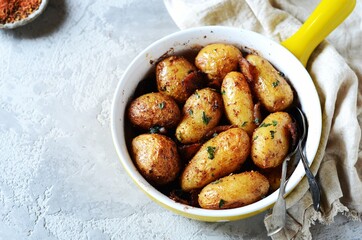 Baked young potatoes with bacon on a gray background, still life