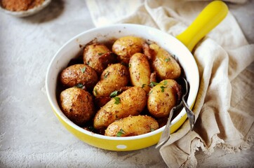 Baked young potatoes with bacon on a gray background, still life