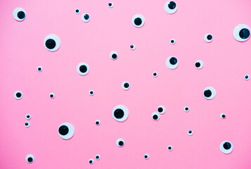 A pattern of cartoon toys eyes on a pink minimalistic background.