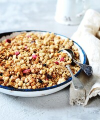 Homemade granola with berries and nuts in a bowl on a gray background